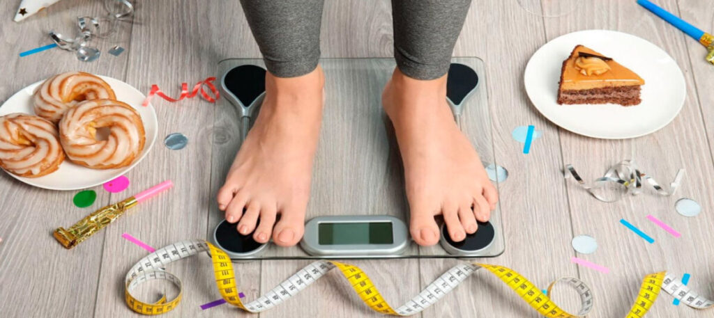 фото: зважування на вазі, тістечка на тарілці – ризик ожиріння