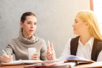 фото: дві дівчини з блокнотами та ручками – команда на роботі