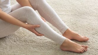 фото: дівчина сидить на підлозі – ломота в тілі перед дощем