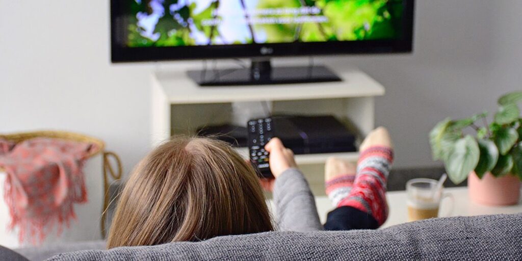 фото: дівчина на дивані дивиться телевізор – підбірка фільмів