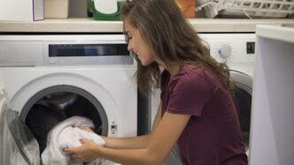 фото: дівчина дістає одяг з пральної машини – як правильно прати речі