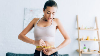 фото: дівчина міряє талію – помилки під час схуднення