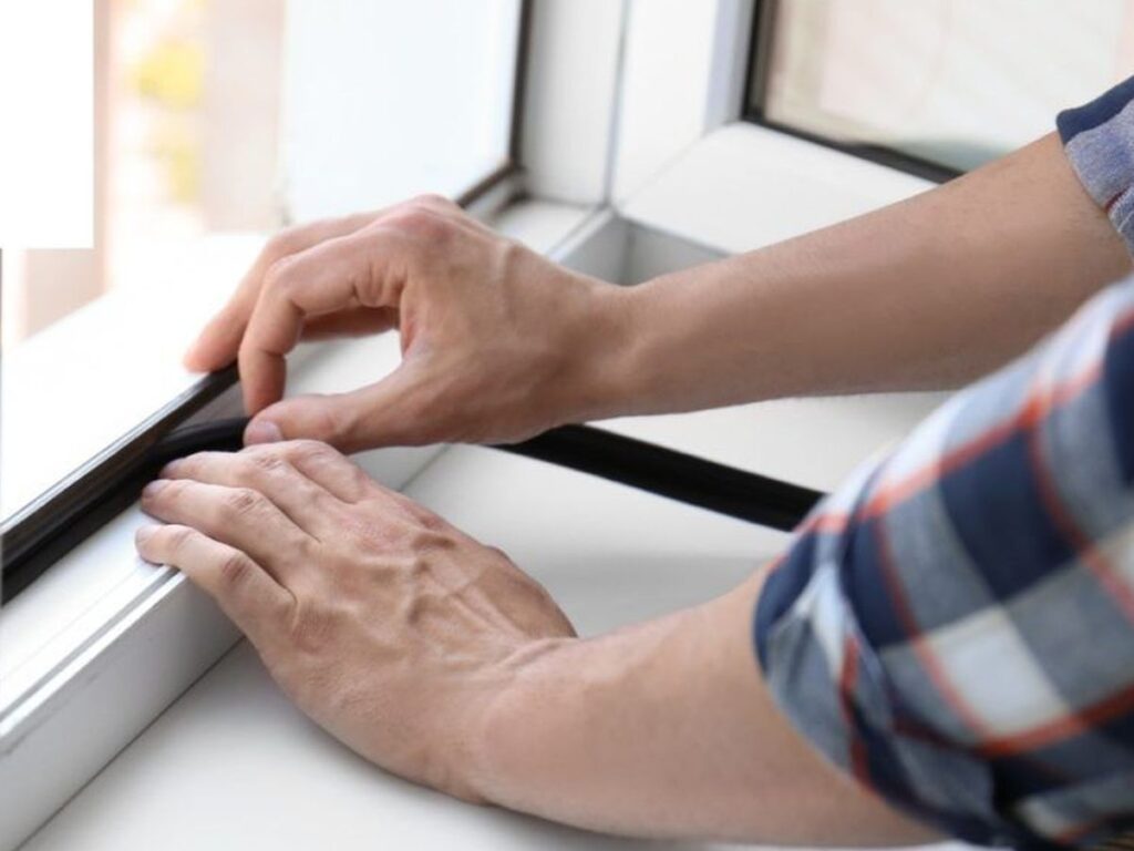 фото: чоловік утеплює вікна – як зберегти тепло