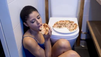 фото: дівчина з булімією їсть піцу біля унітазу – прояви булімії