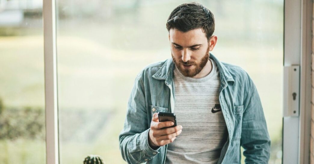 фото: чоловік дивиться у смартфон – технозвички