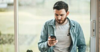 фото: чоловік дивиться у смартфон – технозвички