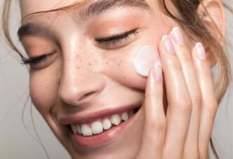 фото: дівчина наносить крем на обличчя - здорова шкіра взимку