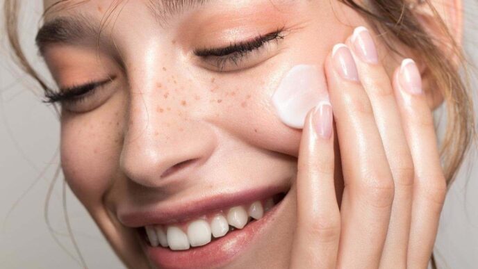 фото: дівчина наносить крем на обличчя - здорова шкіра взимку