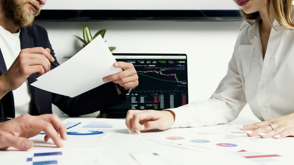 фото: бізнес‑команда аналізує графіки та фінансові дані на ноутбуці під час обговорення стратегії ціноутворення в офісі