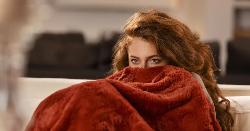 фото: жінка, закутана в пледі — як зігрітися в квартирі без опалення