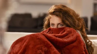 фото: жінка, закутана в пледі — як зігрітися в квартирі без опалення