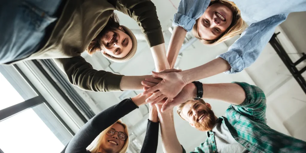 фото: усміхнена команда бізнесу, яка піднімає руки разом – ілюстрація командної роботи та ефективної співпраці