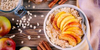 фото: Класична вівсянка з яблуком і корицею – тарілка гарячої каші з нарізаним яблуком, посипана корицею, на дерев’яному столі