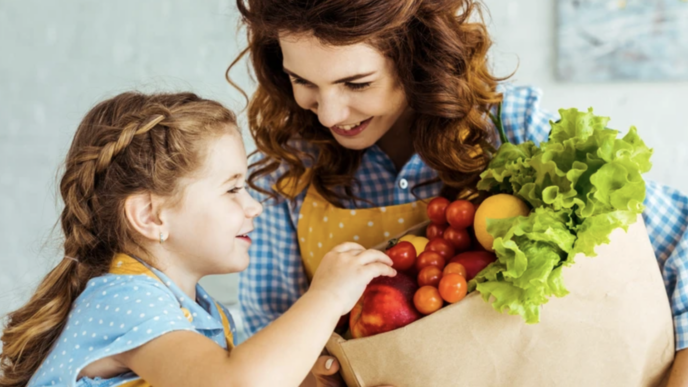 фото: жінка з дитиною тримає пакет корисних продуктів